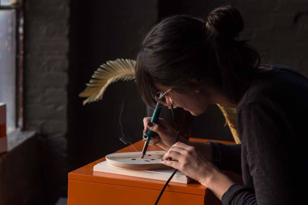 woman using soldering iron for pyrography wood burning